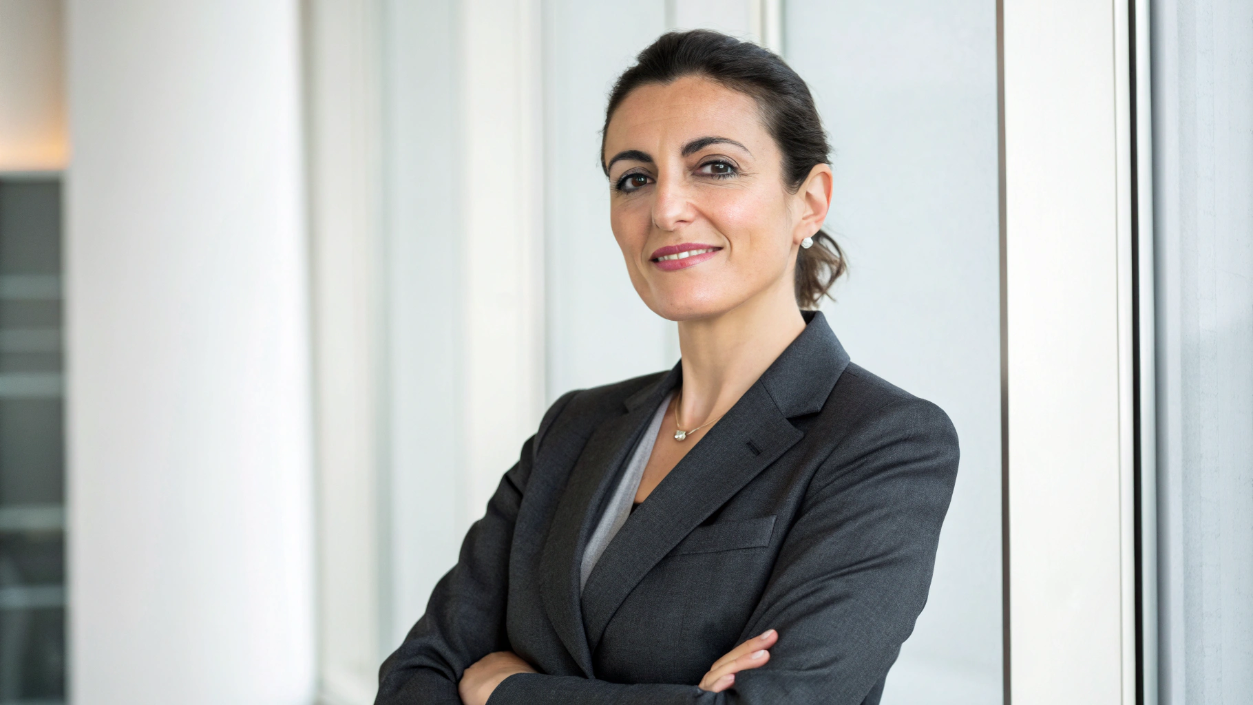 A professional headshot of a woman wearing charcoal gray suit in well-lit office